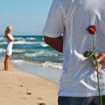 loving couple, man with rose waiting his woman on the sea beach